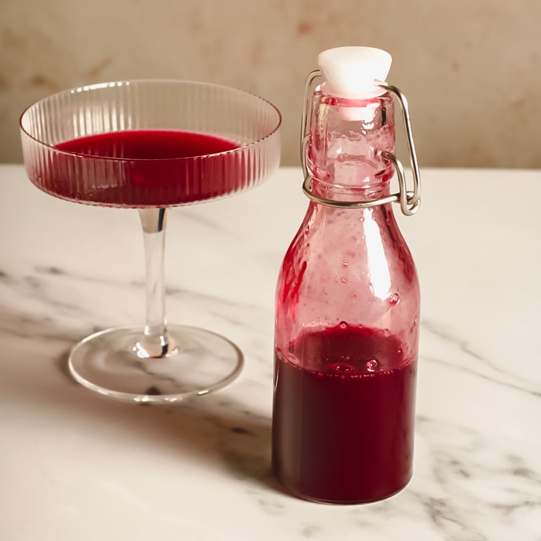 Schisandra berry syrup in a jar and a coupe glass