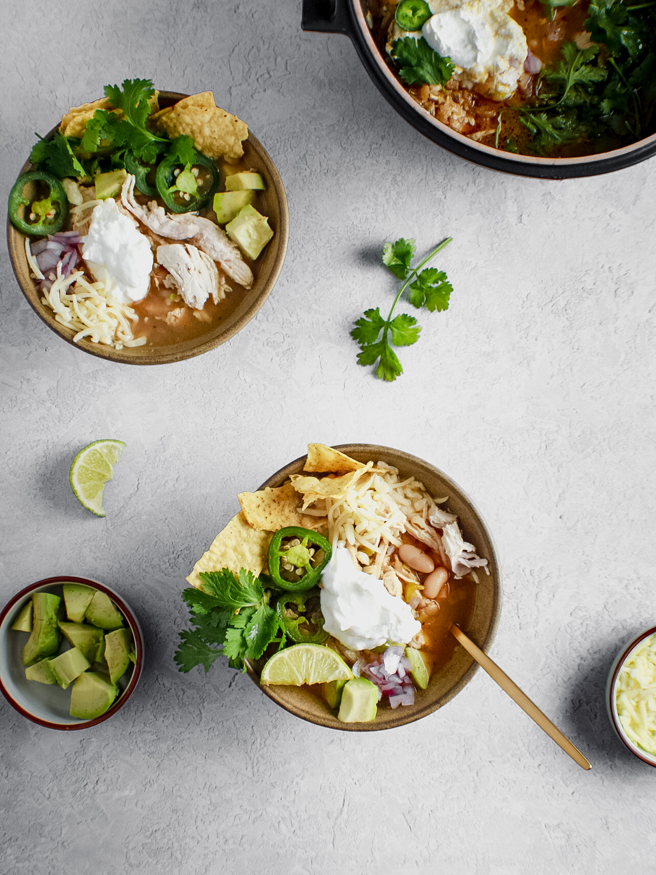 Bowls of white bean chicken chilli with avocado on the side