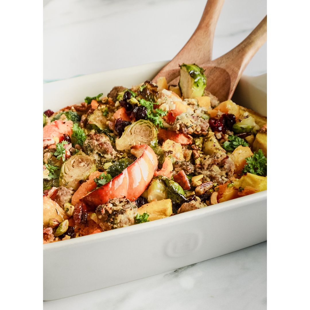 Acorn and butternut squash and sausage casserole with wooden spoons in dish to serve