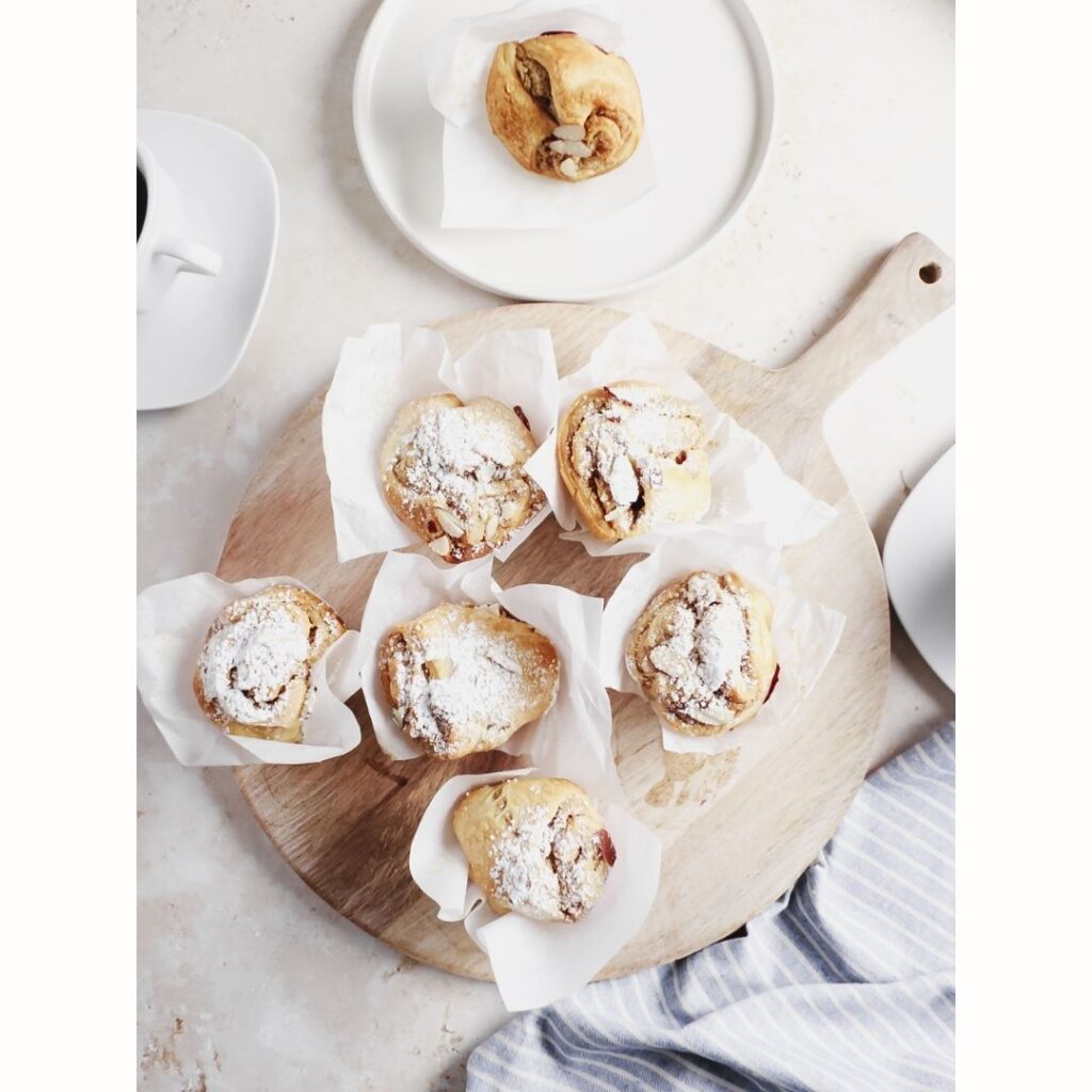 Almond pastries with icing sugar on top. On wooden board