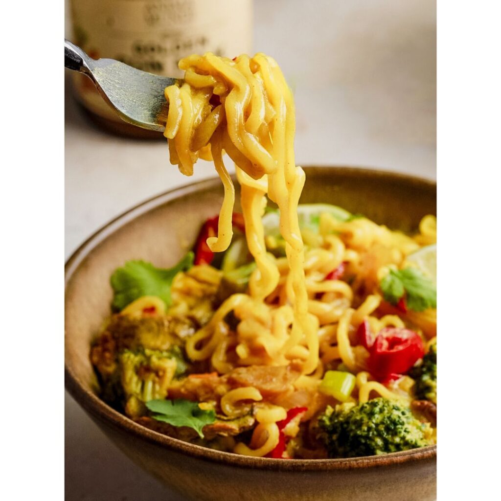 Yellow noodles in brown bowl of veggies