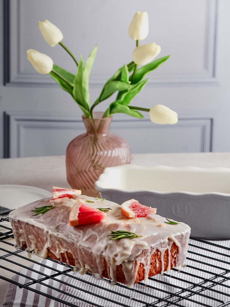 cake on wire rack with white tulips in background