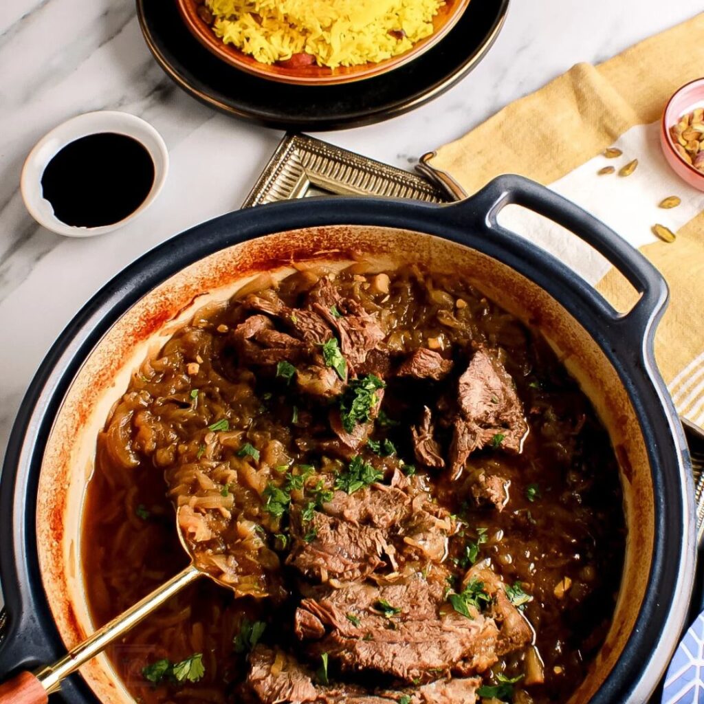 Sephardic beef in a pot on table with yellow rice on the side